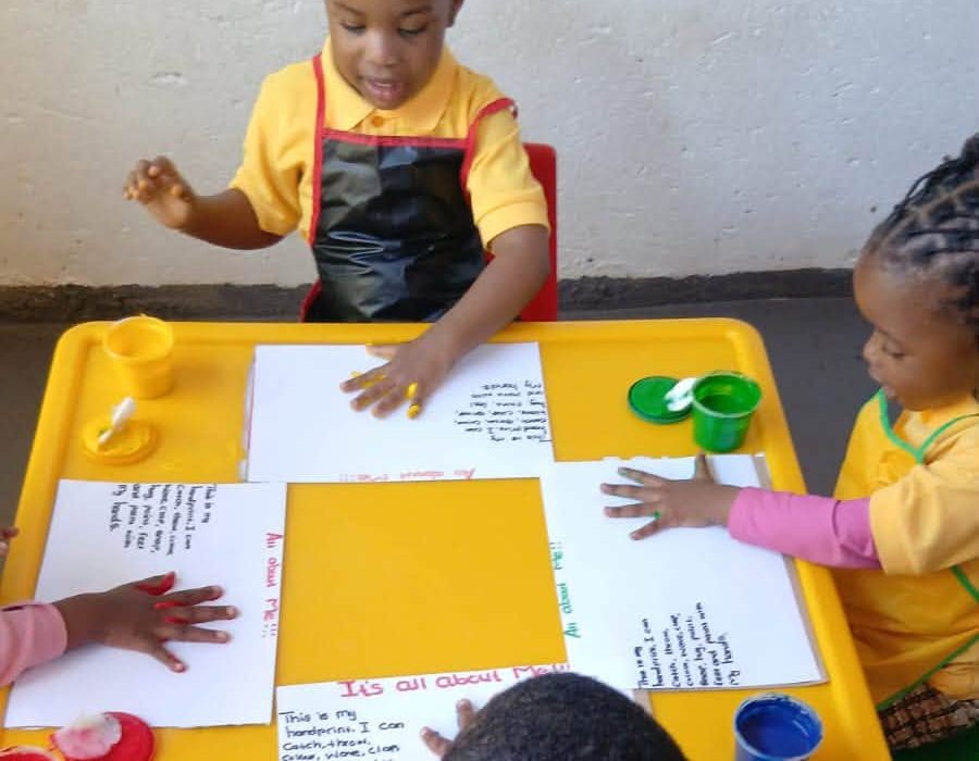 Grade R children completing handprint painting worksheets at their table