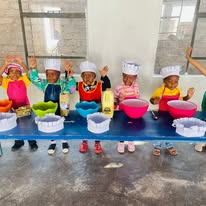 Butterfly Class children in chef hats and aprons at a baking activity at Twinkle Toes